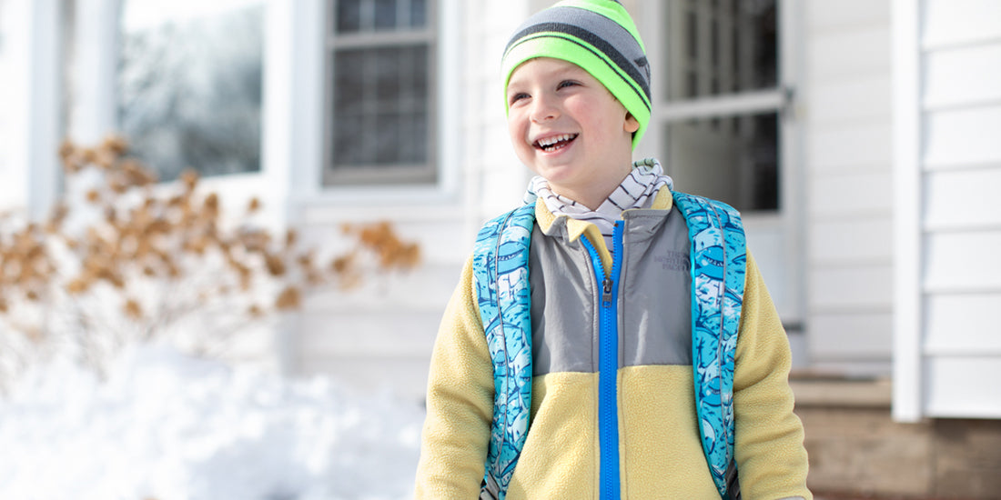 Child wearing a colorful winter outfit in front of a house. The jacket features a MagZip Magnetic Zipper Top Stopped Round Base #5