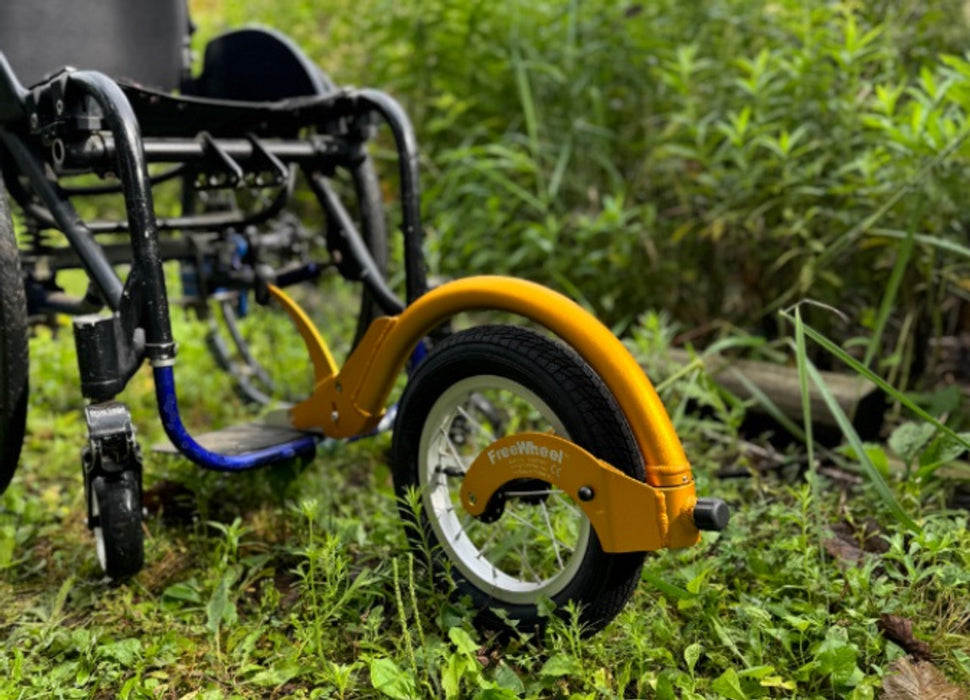 Detail of a FreeWheel Wheelchair Attachment Gold on a wheelchair outdoors.