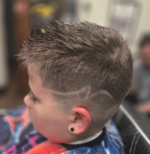 Child with a styled haircut in a barbershop setting