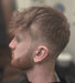 Man with a styled haircut and beard in a barbershop setting