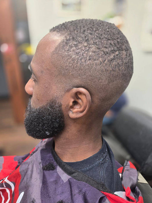 Man with a styled haircut and beard in a barbershop setting