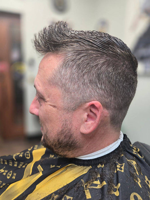 Man with a styled haircut wearing a black and yellow barber cape