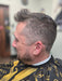 Man with a styled haircut wearing a black and yellow barber cape