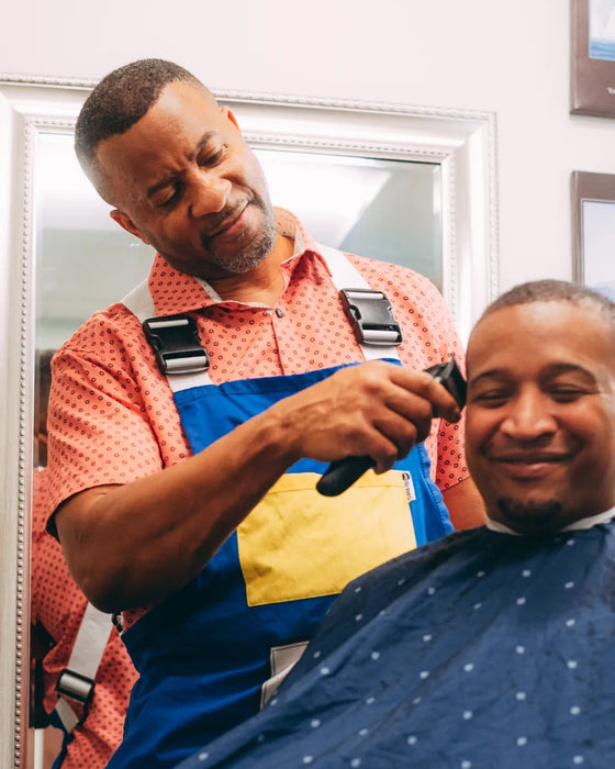 Team Amplife® Ambassador Travis Sanders cutting a customer's hair in a barber shop