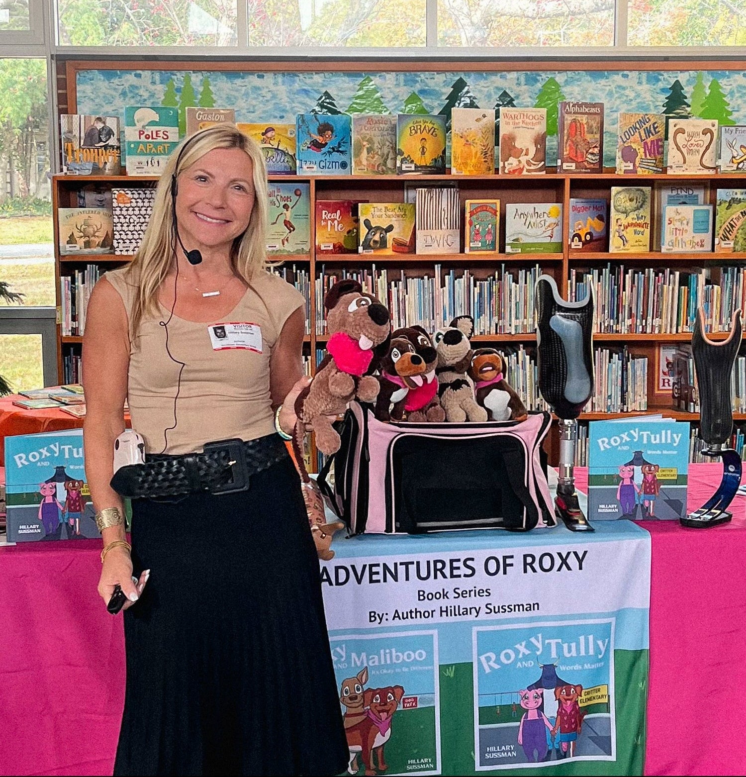 Hillary Sussman standing in front of a display of the Adventures of Roxy book series with stuffed animals and books in a school setting.