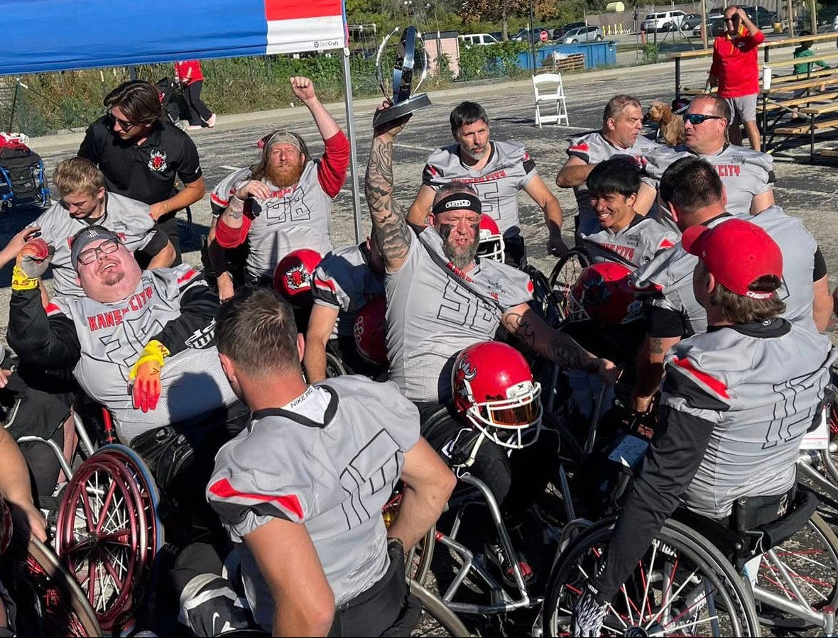 Team Amplife® Ambassador Jason Loftiss lifting up a championship trophy, surrounded by his wheelchair football teammates