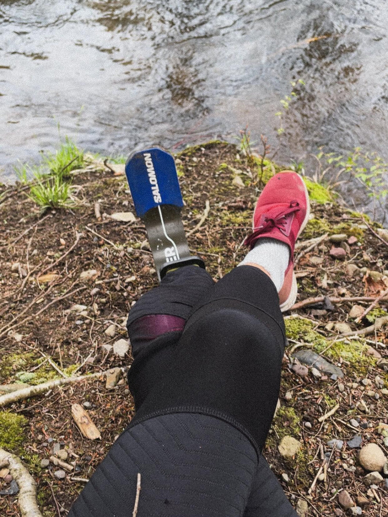 Team Amplife® Ambassador Jenny Morgan sitting with her legs crossed on the edge of a river bed