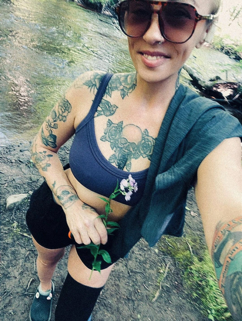 Team Amplife® Ambassador Jenny Morgan holding a flower near a river bed