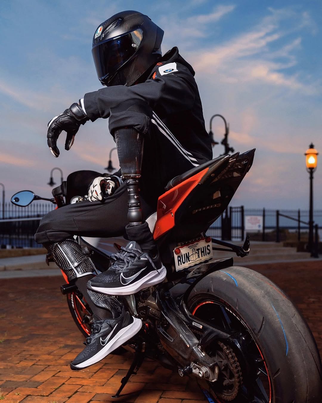 Team Amplife® Ambassador Joseph Forde on a motorcycle with a helmet and black jacket at sunset