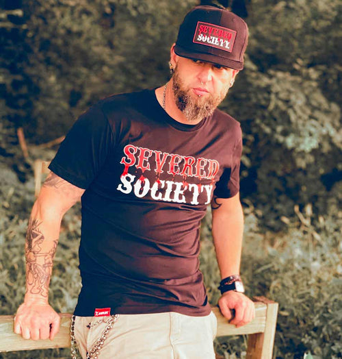 Amplife® supporter wearing the Severed Society® Drip Hat and T-shirt leaning against a fence