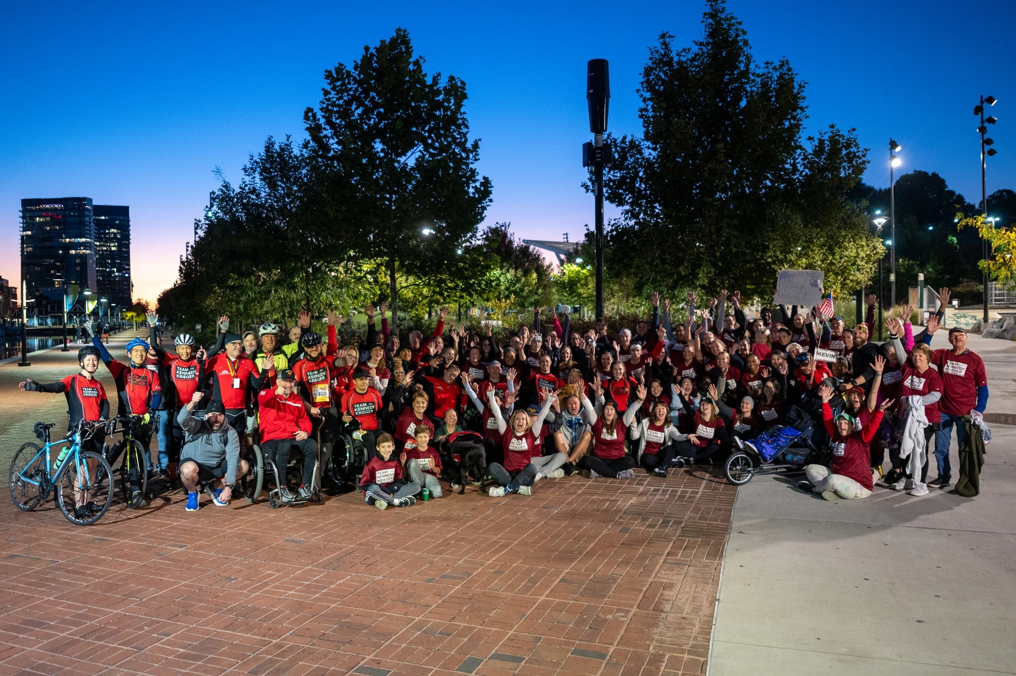 Large group of people in red shirts for Kennedy Krieger Institute for a photo outdoors at dusk.