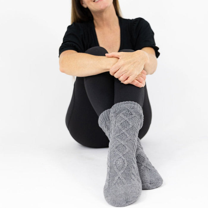 Detail of person sitting on ground with the KickIt Hospital Slipper Socks on a white background