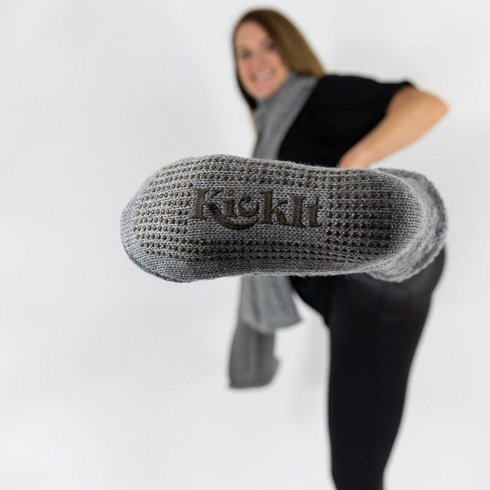Detail of person kicking their leg in the air with the KickIt Hospital Slipper Socks soles being shown on a white background