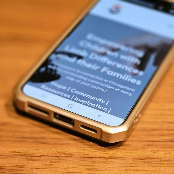 Smartphone displaying a Limb Difference Collective website on a wooden surface