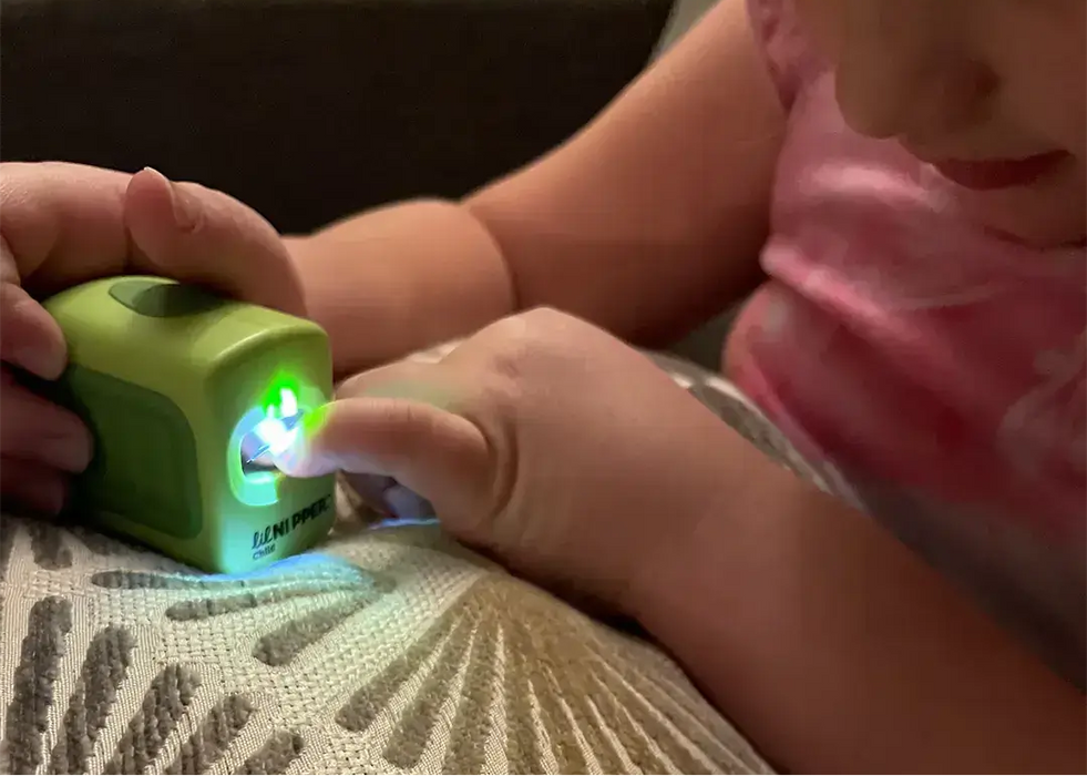 Child's hands using a Lil Nipper Adaptive Electric Nail Clipper