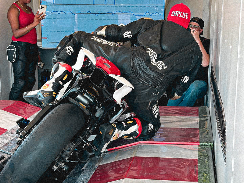 Team Amplife® Ambassador Michael Braxton Jr. wearing the Amplife® Curved Bill Snapback while riding a motorcycle simulator