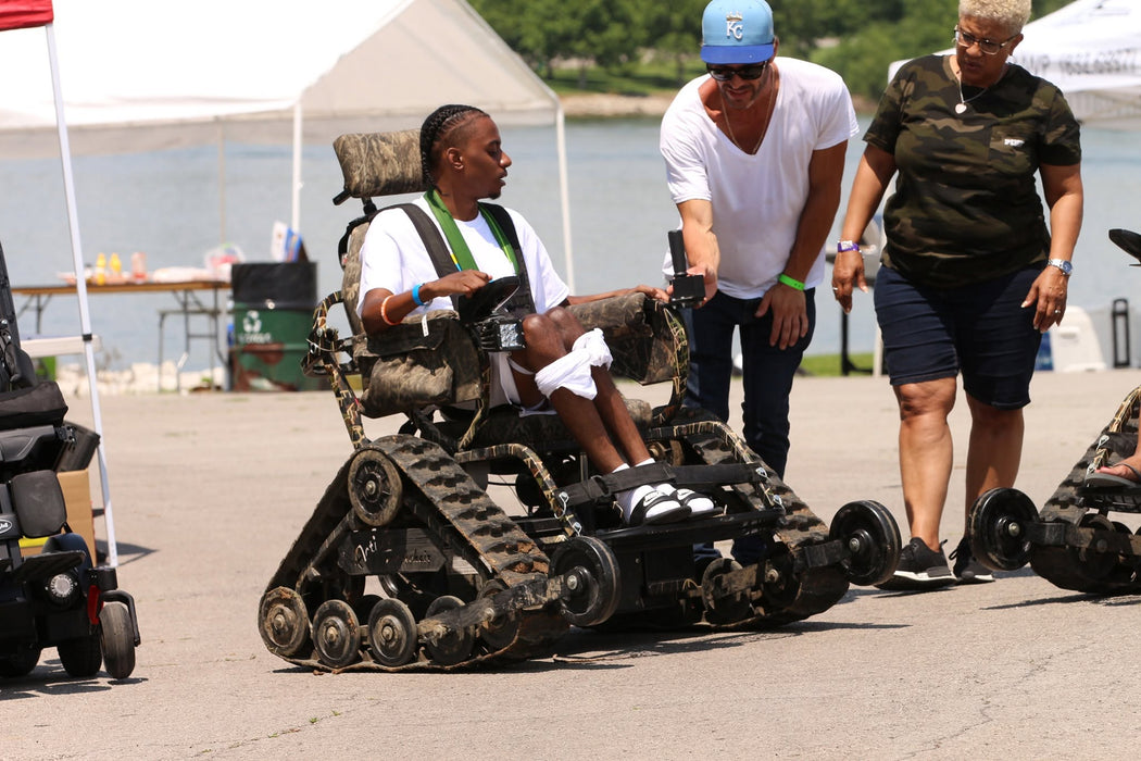 MAS Day at the Lake participant riding in a track chair while interacting with community members 