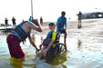 MAS Day at the Lake adaptive water ski participant being assisted with a wheelchair into in the water by multiple volunteers at Smithville Lake