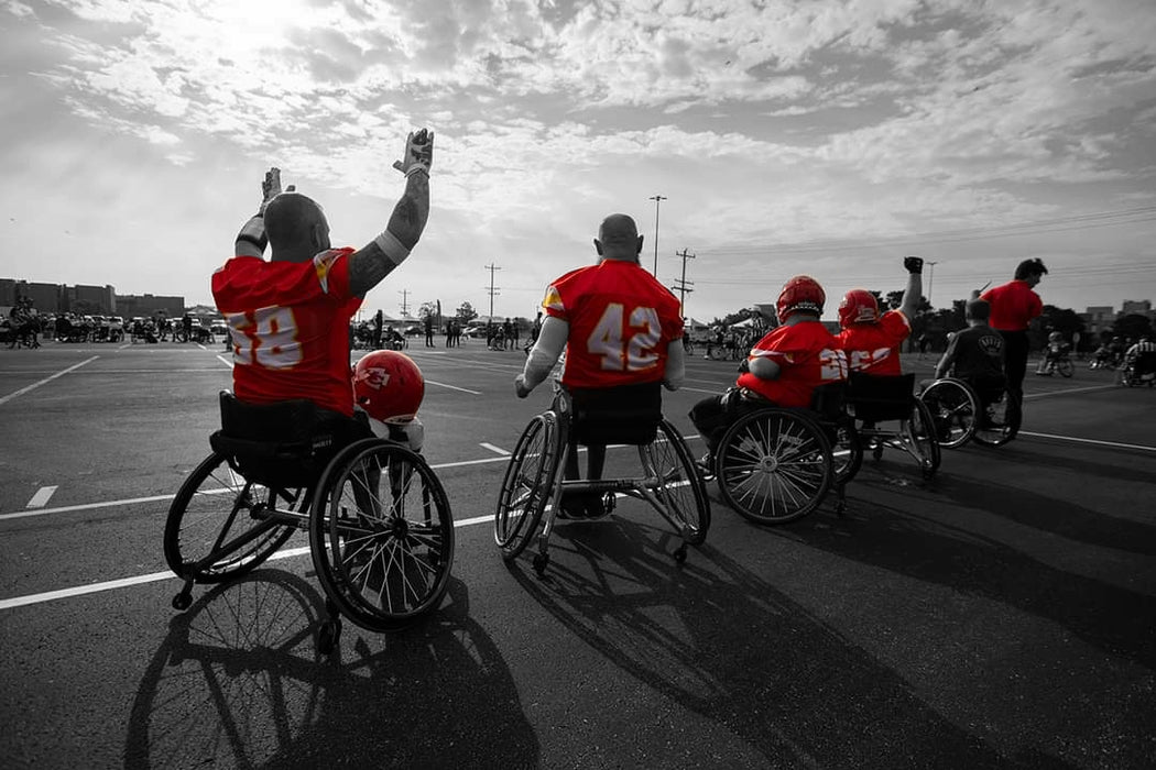 MAS Kansas City Chiefs defender and Team Amplife® Ambassador Jason giving a touchdown sign with his teammates on the sideline