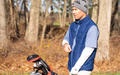 Man wearing the MagZip TeeUp Adaptive Vest with Magnetic Zipper and gray beanie on a golf course with trees in the background.