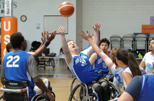 Wheelchair basketball athletes fighting for the ball in the air.