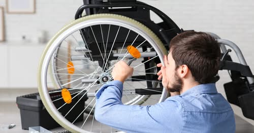Person fixing a wheelchair wheel with tools