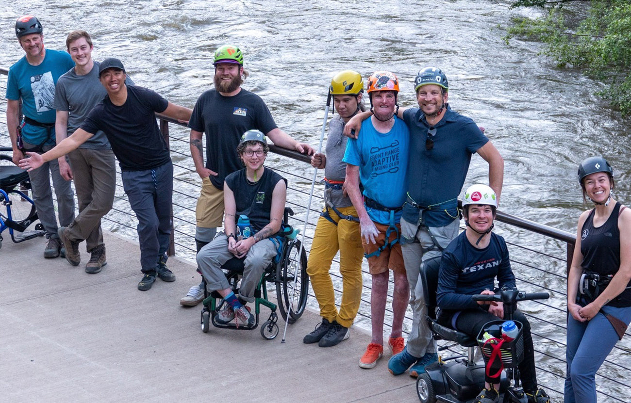 Group photo of Paradox Sports climbers from an outdoor meet up at Clear Creek Canyon. The group is smiling at the camera and the creek is behind them.
