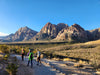Three hikers on a trail with mountains in the background.