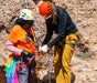 Two climbers preparing for a climb with safety gear on a rocky wall.