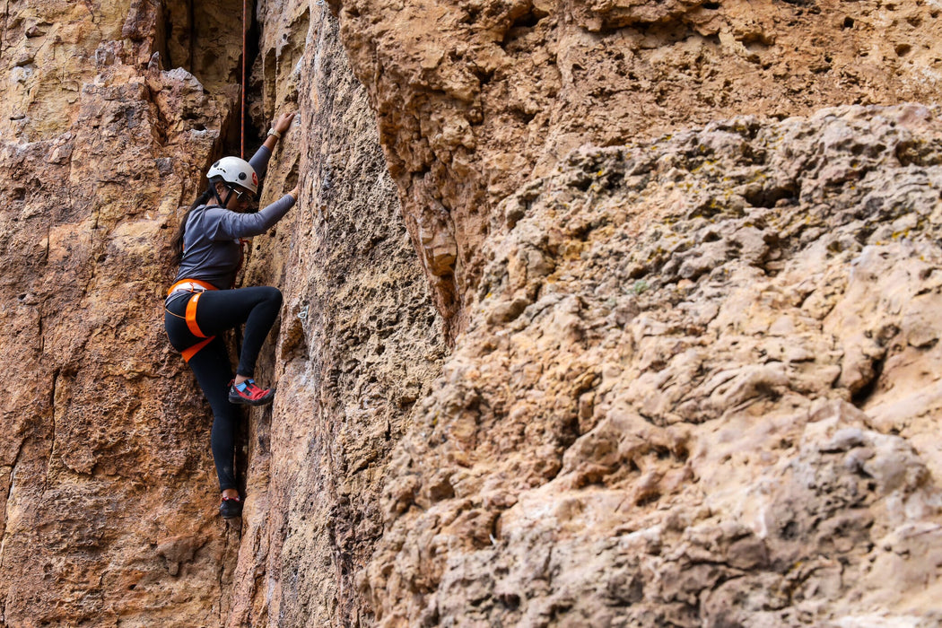 Person climbing a rocky cliff face