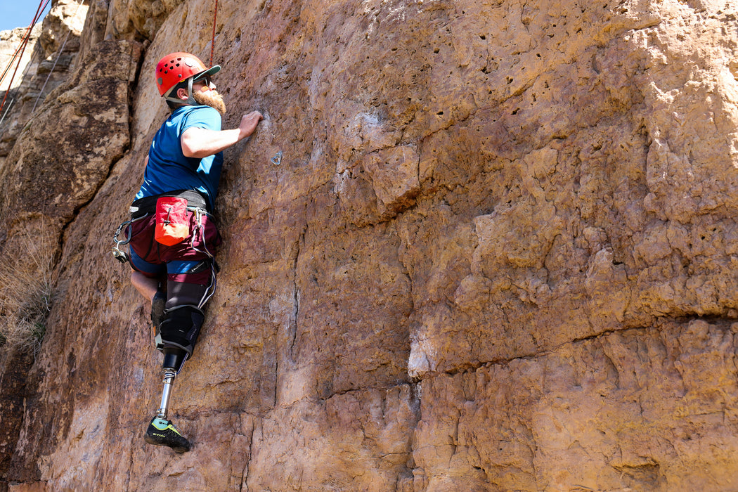 Person with a prosthetic leg climbing a rocky cliff