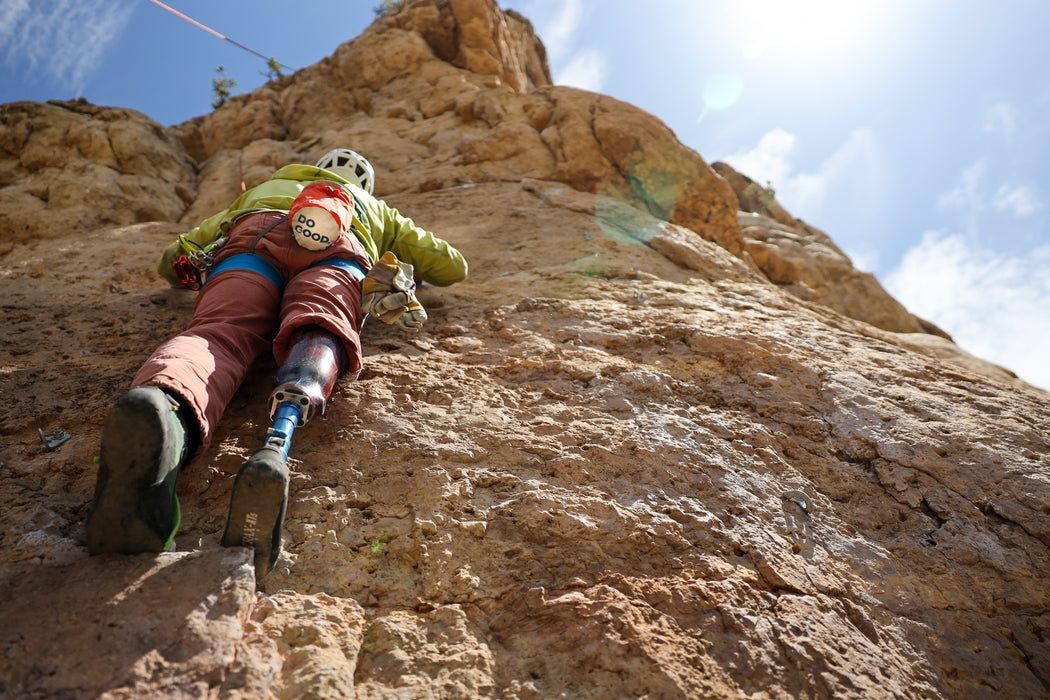 Person with a prosthetic leg climbing a rocky cliff