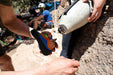 Person holding a prosthetic leg with another person helping attach the foot.