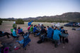 Group of people camping outdoors with mountains in the background.