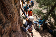 Person climbing a rock face with others in the background