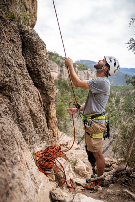 Man climbing a rocky cliff with a helmet and rope