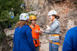 Group of people preparing for a climbing activity with helmets and harnesses.