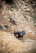Person climbing a rocky cliff with ropes and equipment on a mountain.