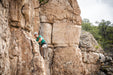 Person climbing a rocky cliff face with a rope