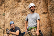 Two climbers with climbing gear standing against a rock wall.