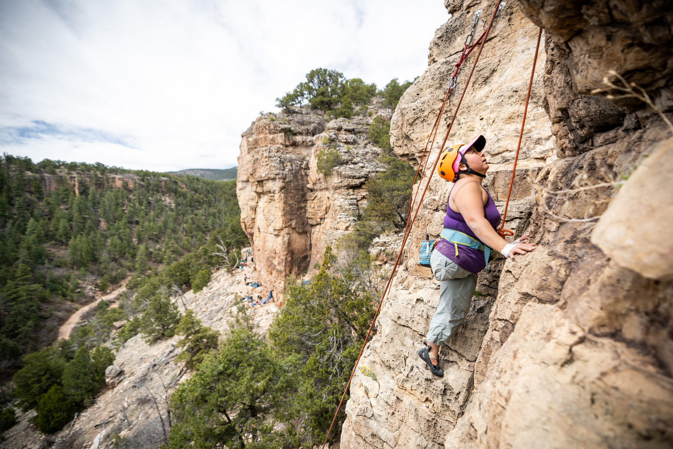 Person rock climbing on a cliff with a scenic landscape in the background