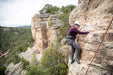 Person rock climbing on a cliff with a scenic background