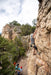 Person rock climbing on a rocky cliff with others below.