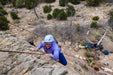 Person rock climbing on a rocky cliff with others in the background