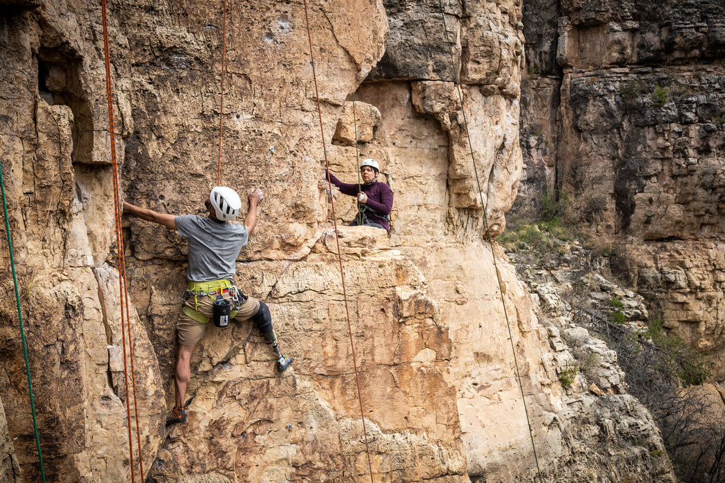 Two climbers on a rocky cliff face with safety ropes.