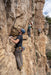 Three climbers on a rocky cliff face with safety ropes.