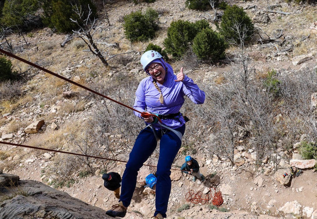 Person on a zip line in a mountainous area with others in the background