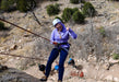 Person on a zip line in a mountainous area with others in the background