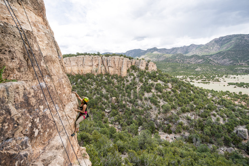 Person rock climbing on a cliff with a scenic landscape in the background