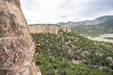 Person rock climbing on a cliff with a scenic landscape in the background